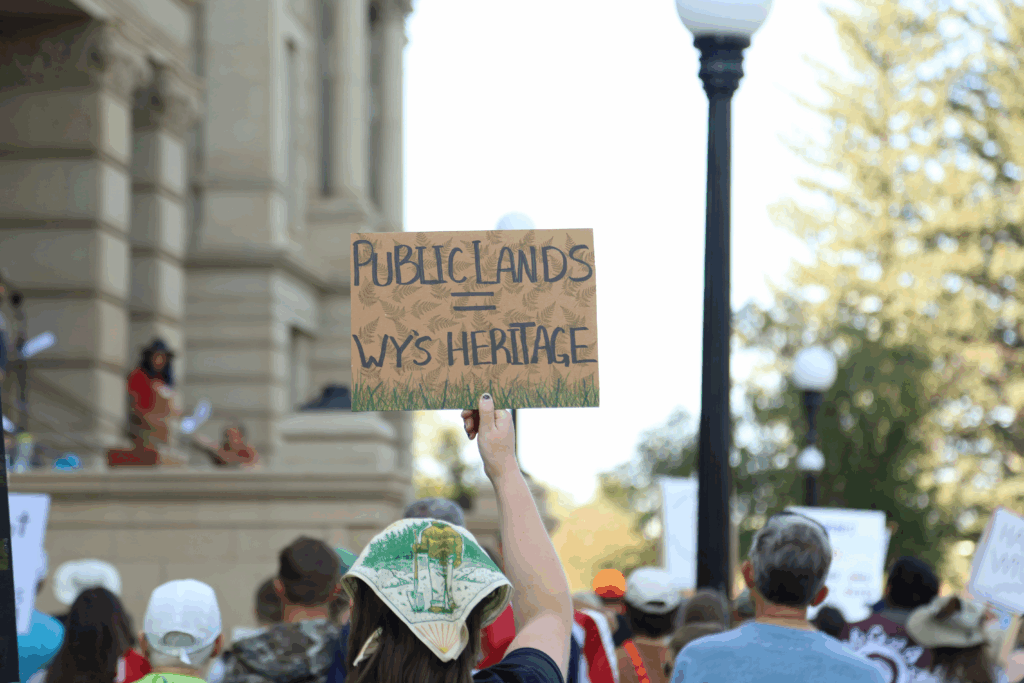 Somone holds up a Public Lands = Wyoming Heritage sign at a rally in Cheyenne